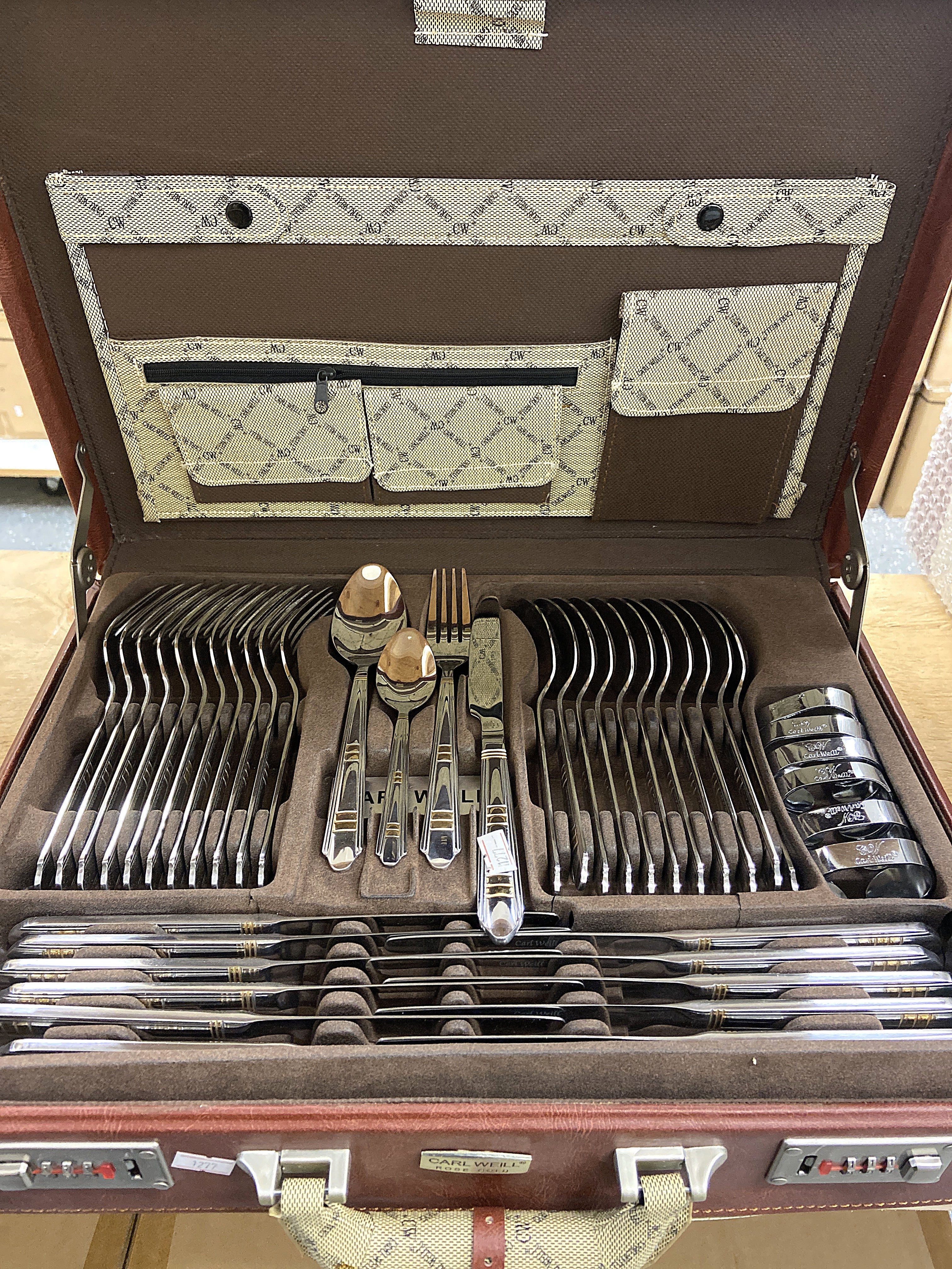Set of silverware in an open brown case with a patterned interior.