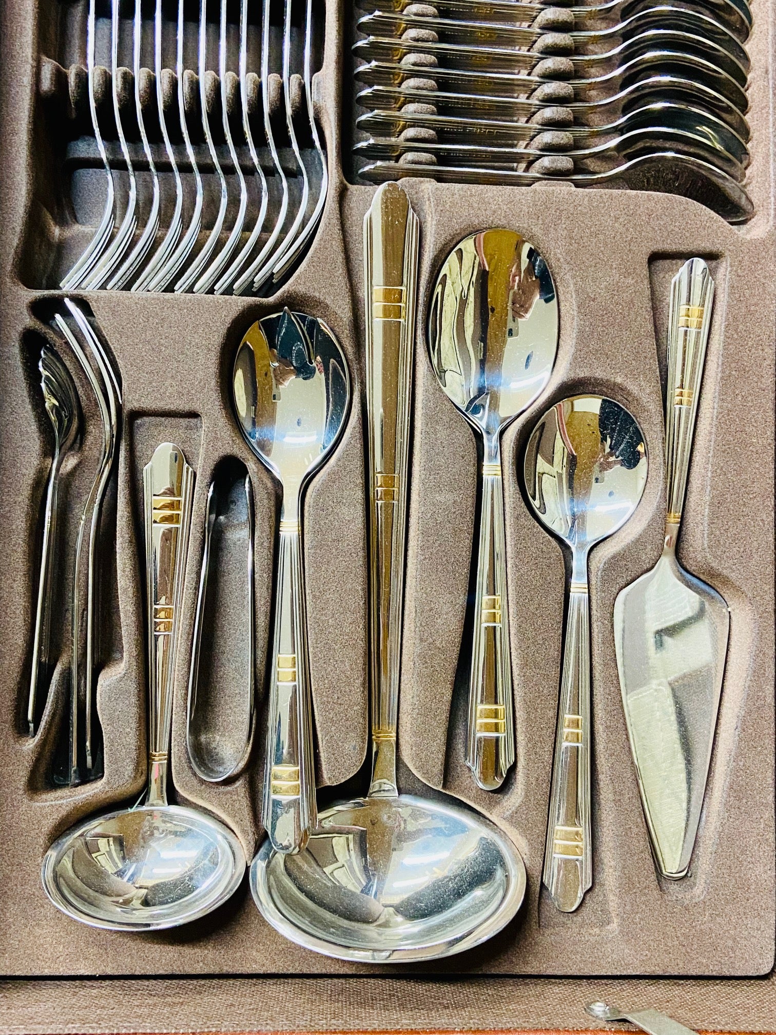 Set of silver cutlery with gold accents in a packaging tray