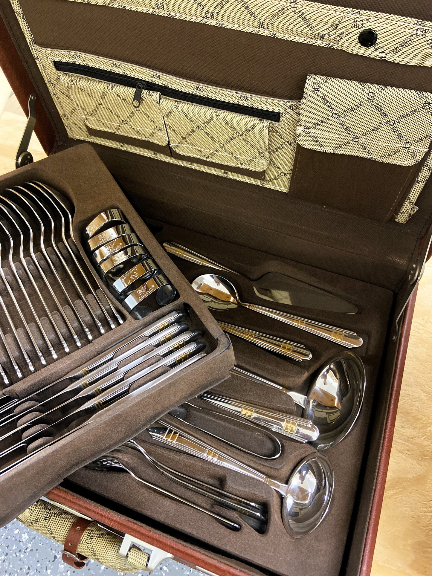 Set of silver cutlery in a brown case with a patterned interior.