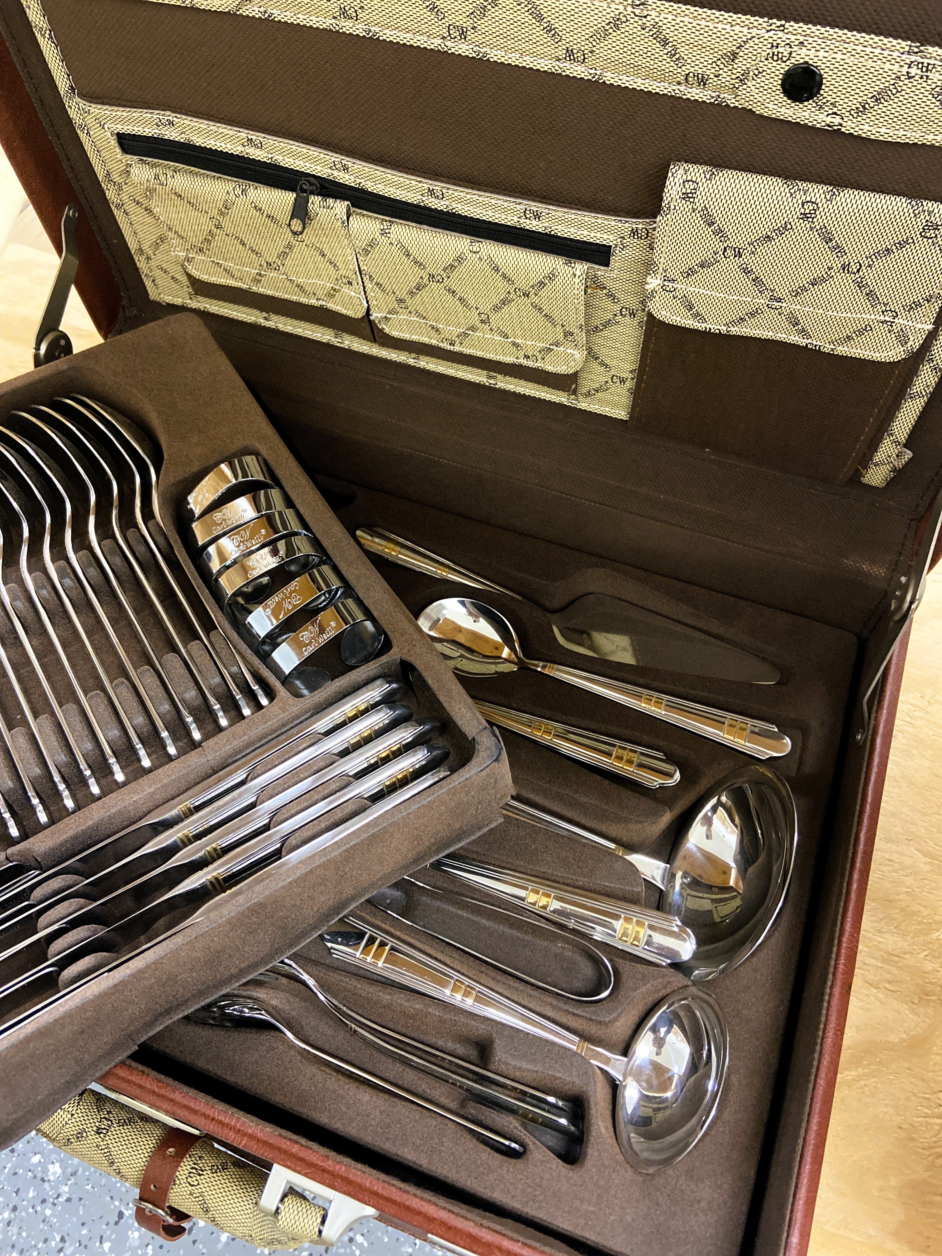 Set of silver cutlery in a brown case with a patterned interior.